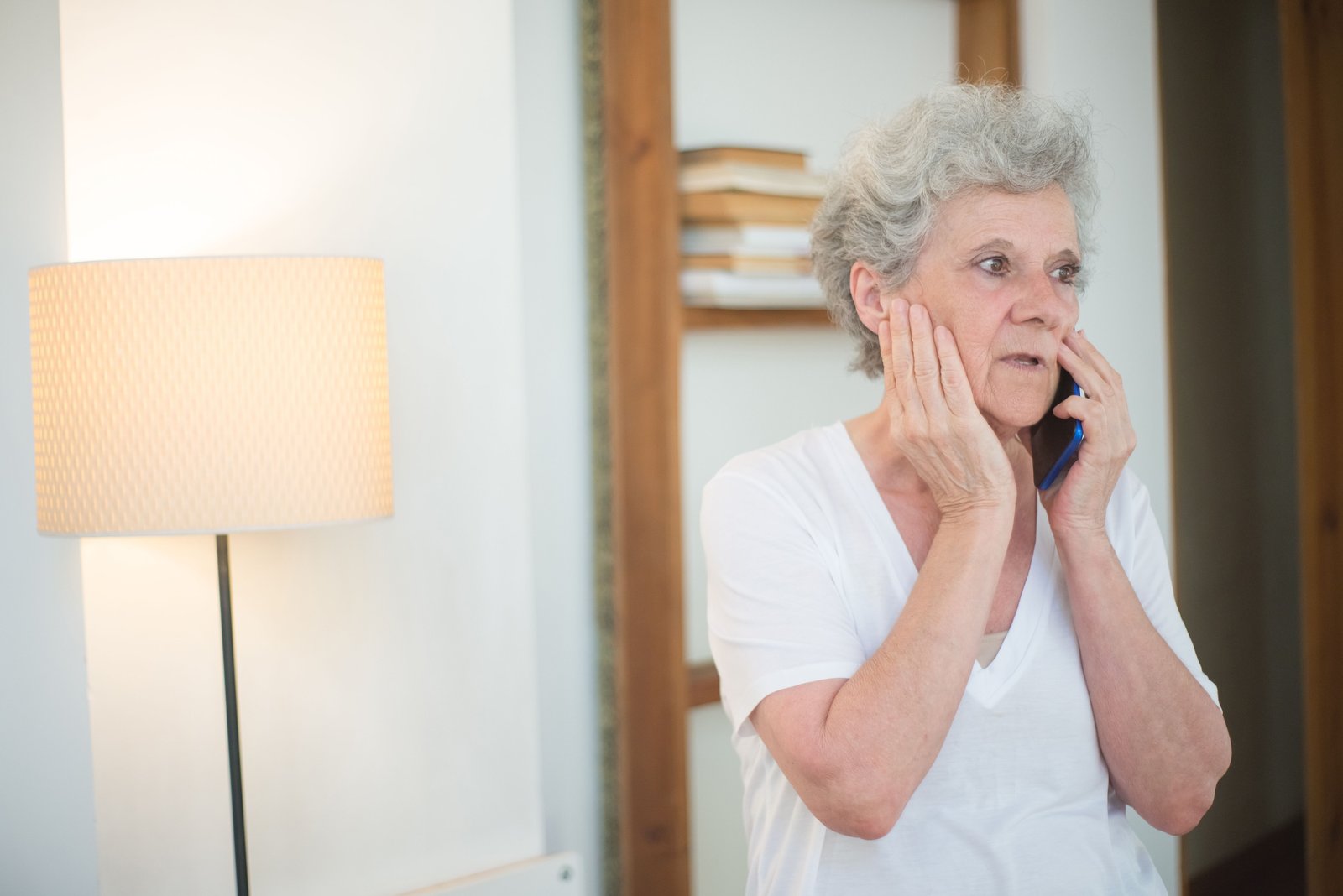 An older woman with her hands at her face, phoning for help with tooth pain