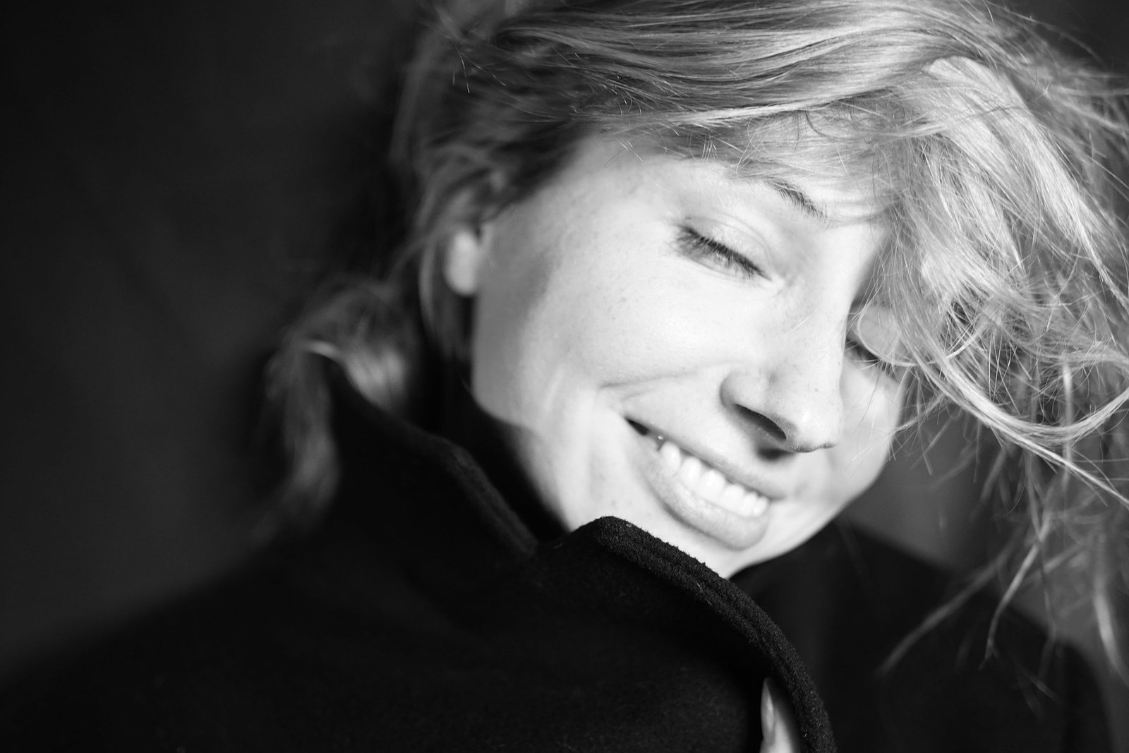 A woman smiling peacefully with closed eyes, in black and white